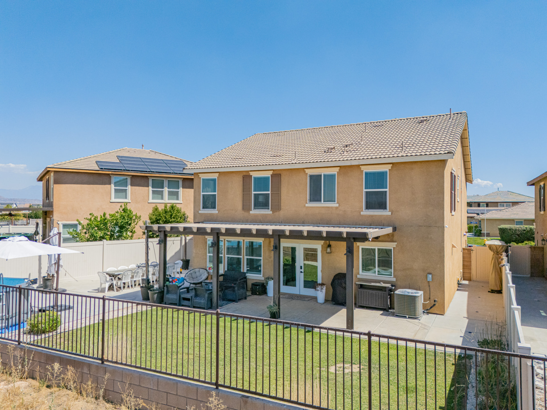 Aerial drone photo of the rear of a two-story home with pool and lawn